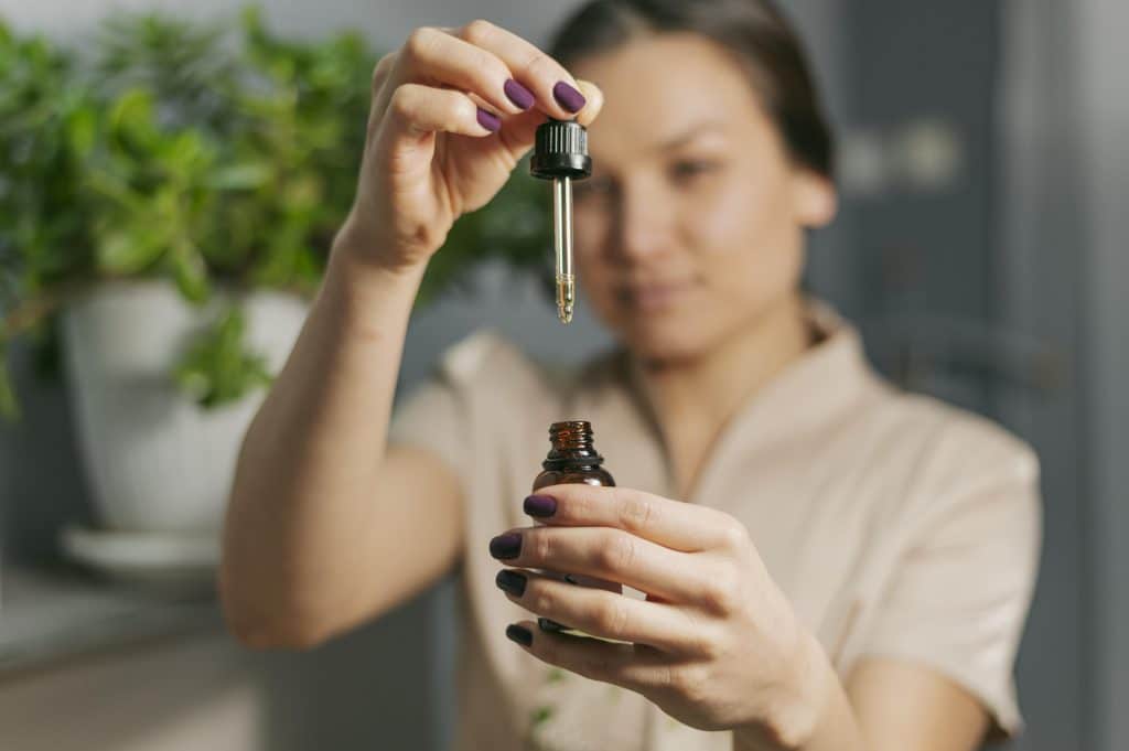 Femme préparant une pipette d'huile naturelle dans un flacon