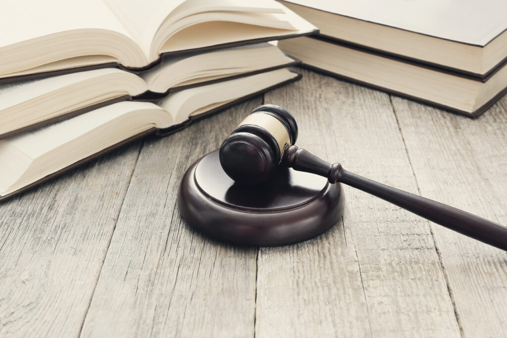 Un marteau de juge posé sur une table en bois, accompagné de livres de droit